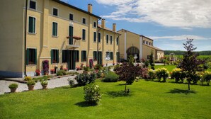 A large, yellow building with multiple windows and a well-maintained garden. - Agriturismo Millefiori Corte delle Rose (Rovigo)