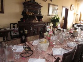 Uma área de refeições com uma mesa posta para uma refeição, cercada por cadeiras.