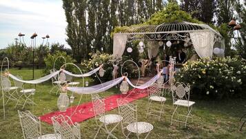 Allestimento per matrimonio all'aperto con un gazebo bianco, sedie bianche e un tappeto rosso.