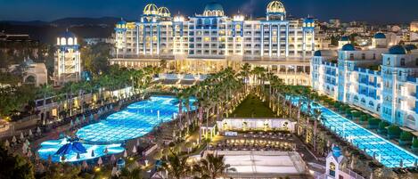 Un hotel grande con varias piscinas, un bar y un escenario para eventos.