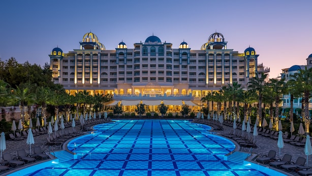 A hotel with a large pool, multiple balconies, and a well-lit facade. - Rubi Platinum Spa Resort & Suites - All Inclusive (Alanya)