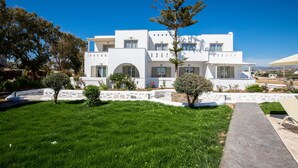 A modern white building with a stone pathway leading to a seating area. - Evdokia (Naxos)