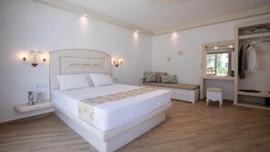 A bedroom with a large bed, bedside tables, a bench, a wardrobe, and a mirror. - Evdokia (Naxos)