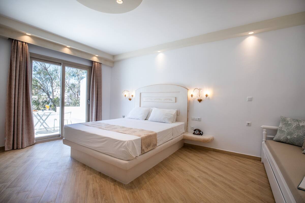 A modern bedroom with a large bed, a bedside table, and a view of the outdoors.