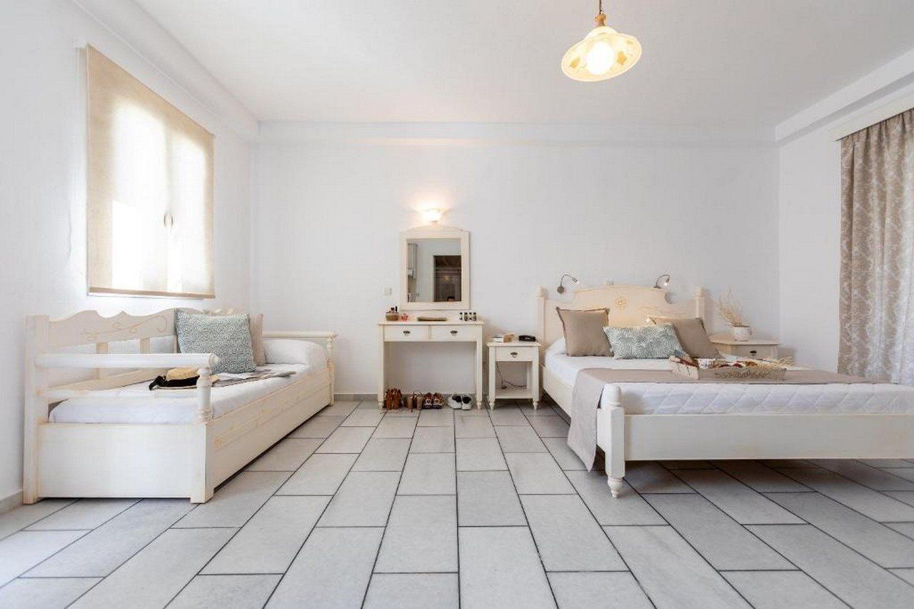 Une chambre avec deux lits simples, un bureau, une chaise, un miroir et un luminaire suspendu.