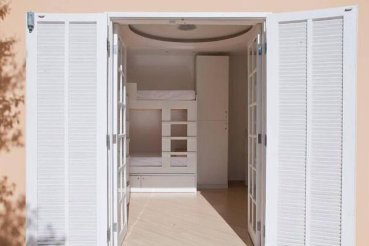 A room with a bunk bed, built-in shelving, and a wardrobe.