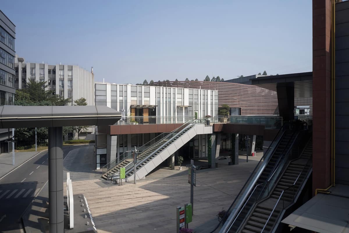 Een modern gebouw met een overdekte gangpad, twee trappen en een heldere lucht.