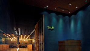 Een modern interieur met een receptiebalie, houten details en een blauwe muur met een neonbord.