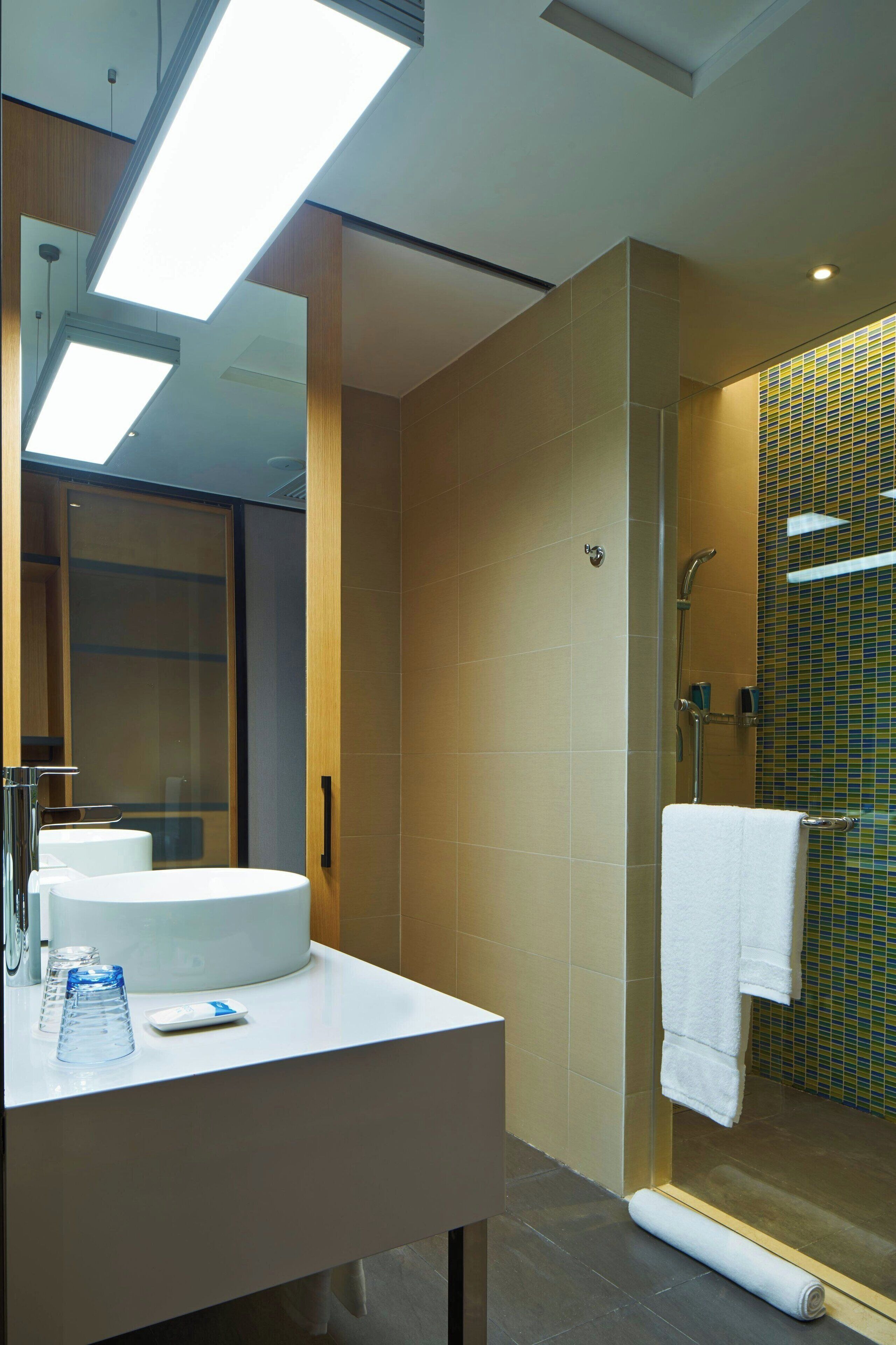 A modern bathroom with a white sink, a glass shower enclosure, and a towel rack.