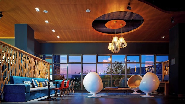 Een modern interieur met een gebogen houten plafond, grote ramen, een blauwe bank en unieke, bolvormige stoelen.