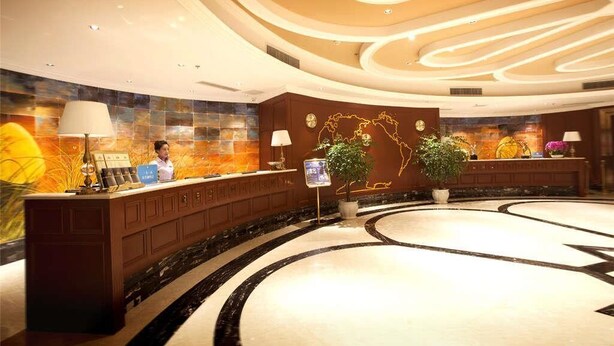 A hotel reception area with a curved reception desk, a large wall mural, and a central decorative plant. - Days Inn Chongqing Guangyu (Chongqing)
