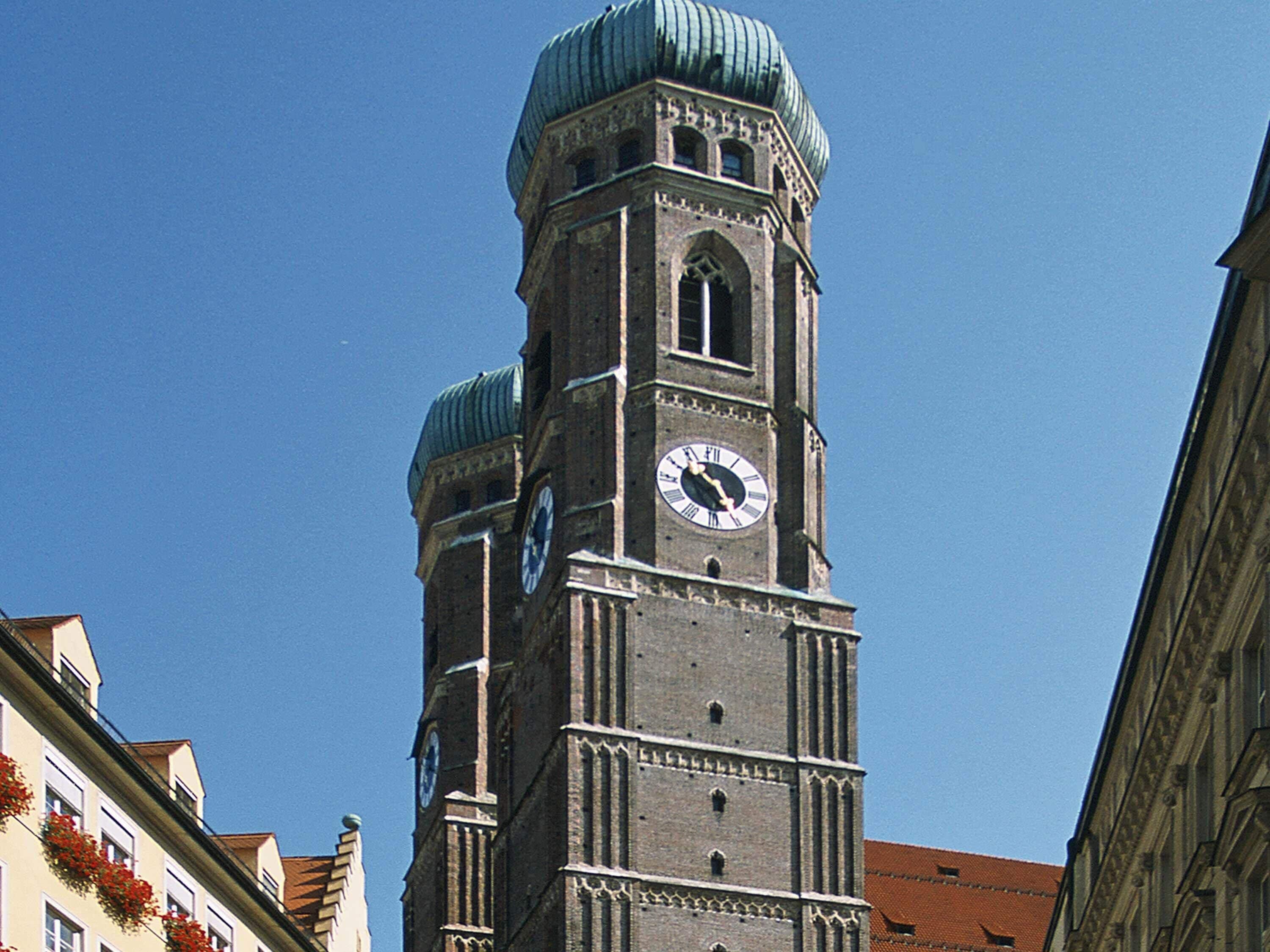 Een hoge klokkentoren met een koepel en een kleinere klok aan de zijkant.