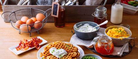 A breakfast setting with waffles, eggs, bacon, and various condiments.