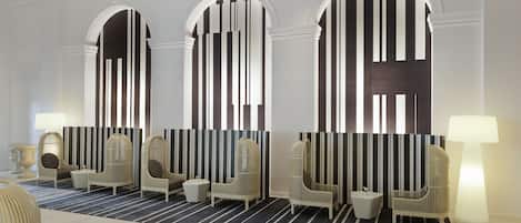 Un vestíbulo con tres puertas arqueadas, un muro a rayas y una zona de estar con sillas y una mesa.
