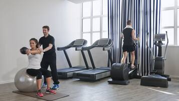 Een sportschool met loopbanden, een fitnessbal en een roeimachine.