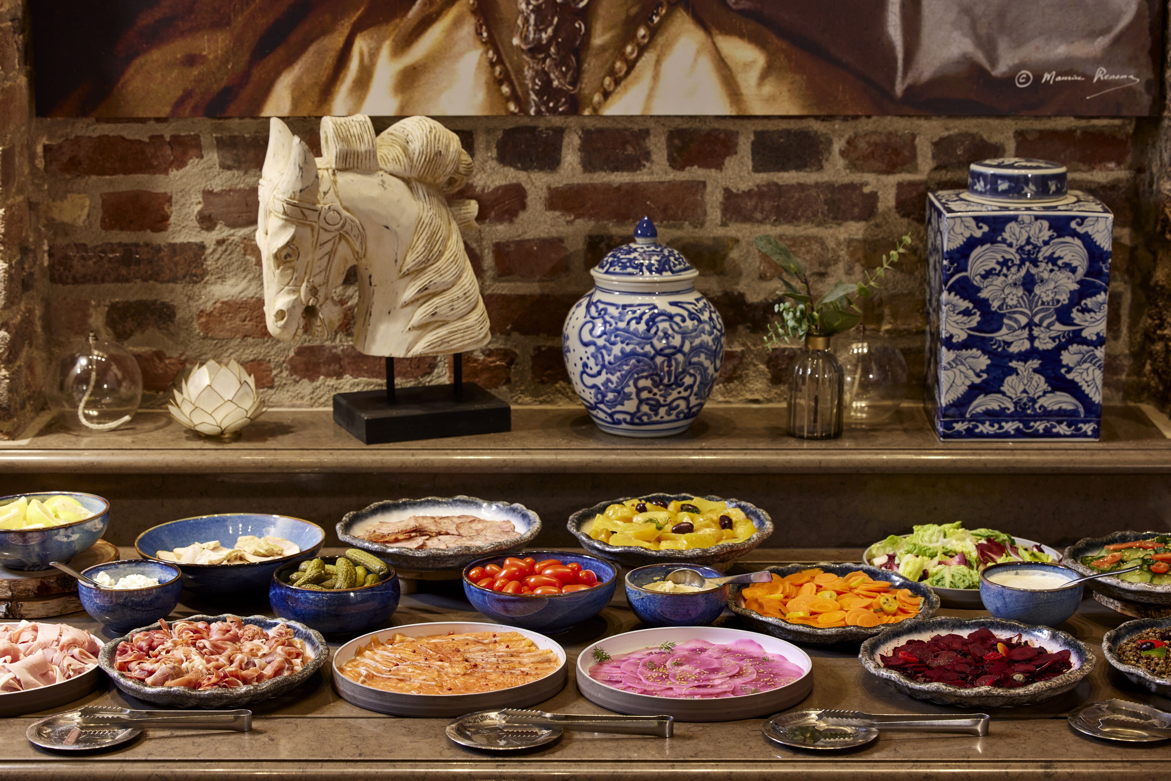 A buffet with various dishes and a decorative horse head sculpture.