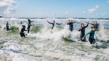 A group of people in wetsuits surfing in the ocean.