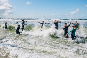 Un grupo de personas con trajes de neopreno surfeando en el océano.