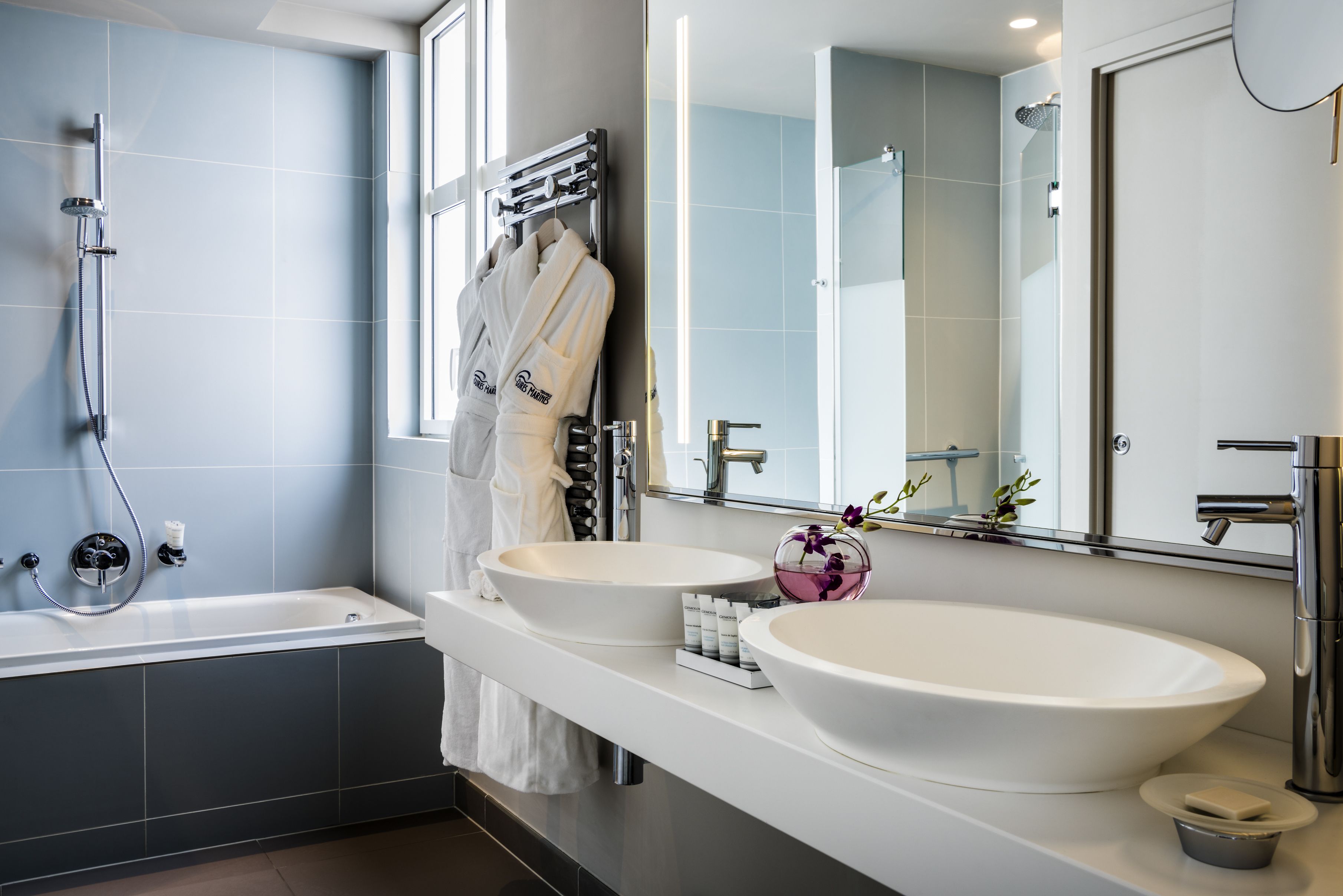 A modern bathroom with two sinks, a bathtub, and a shower.