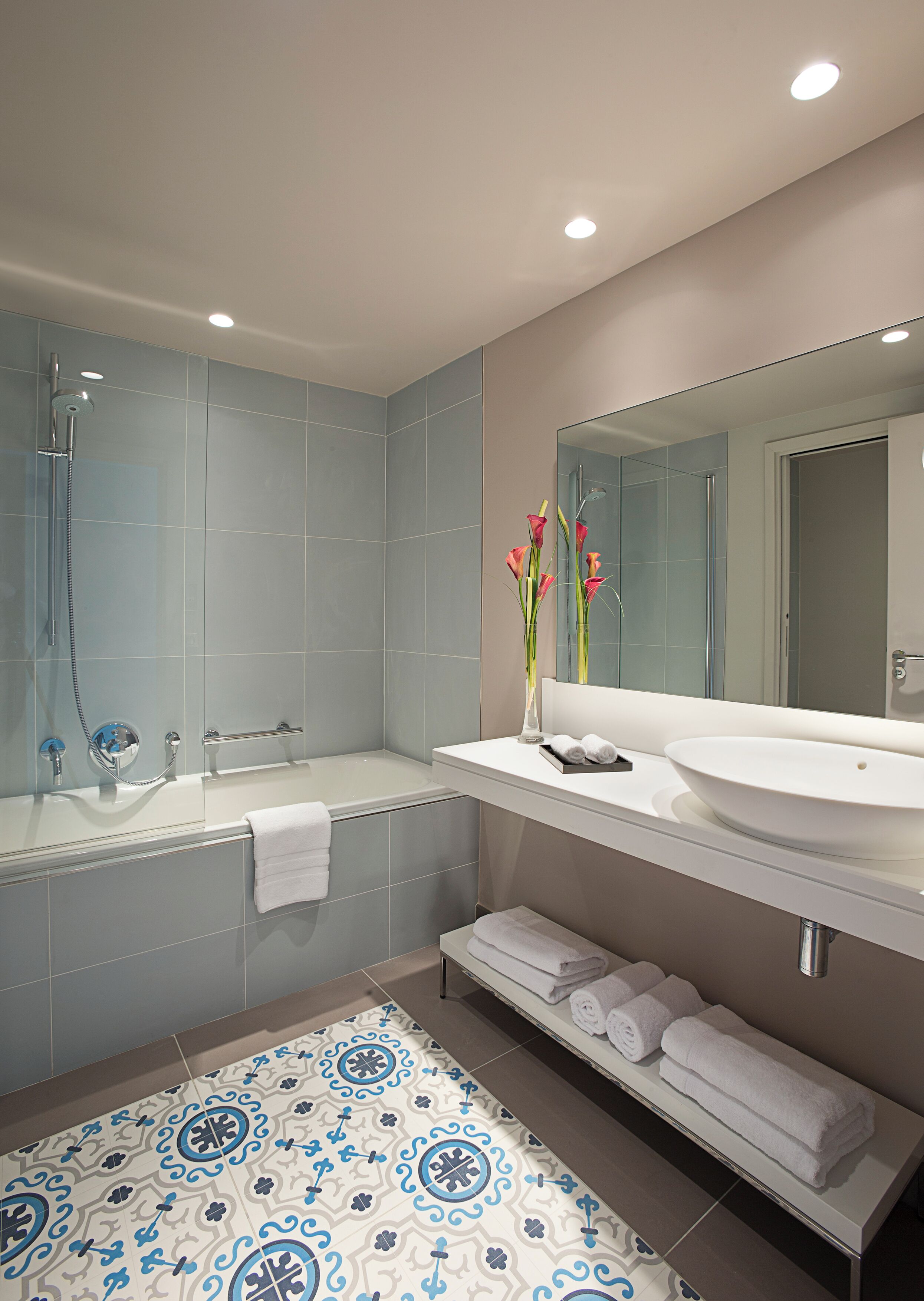 A modern bathroom with a bathtub, shower, and sink.