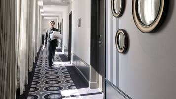 A hotel corridor with a patterned carpet, a person walking, and three wall-mounted mirrors.
