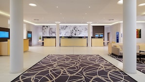 A modern hotel lobby with a reception desk, seating area, and a patterned carpet. - Novotel Nuernberg Centre Ville (Nuremberg)