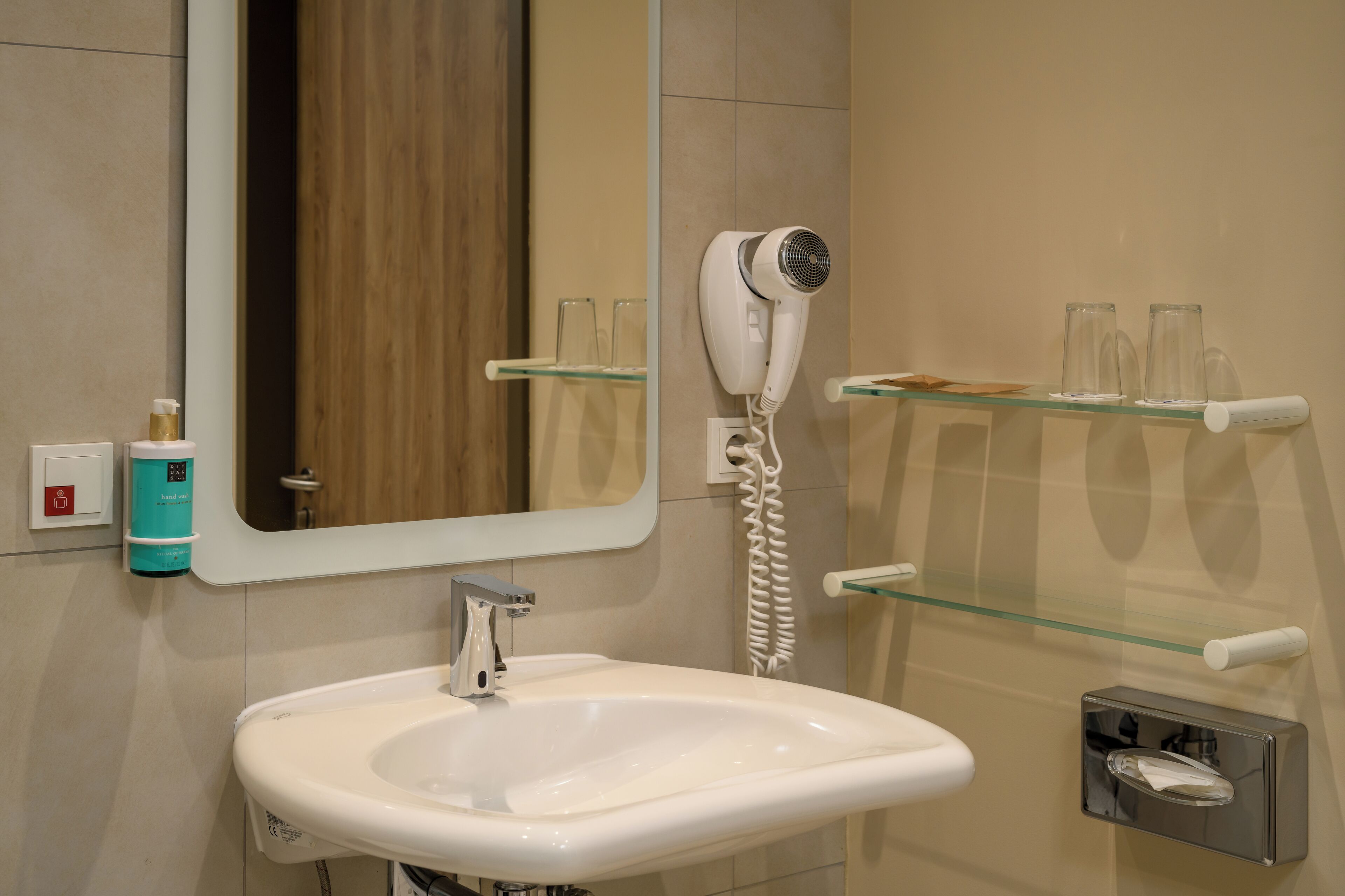 Un baño con lavamanos blanco, secador de pelo y espejo.