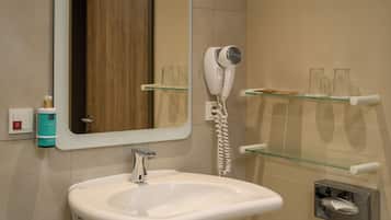 Un baño con lavamanos blanco, secador de pelo y espejo.