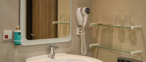 Un baño con lavamanos blanco, secador de pelo y espejo.