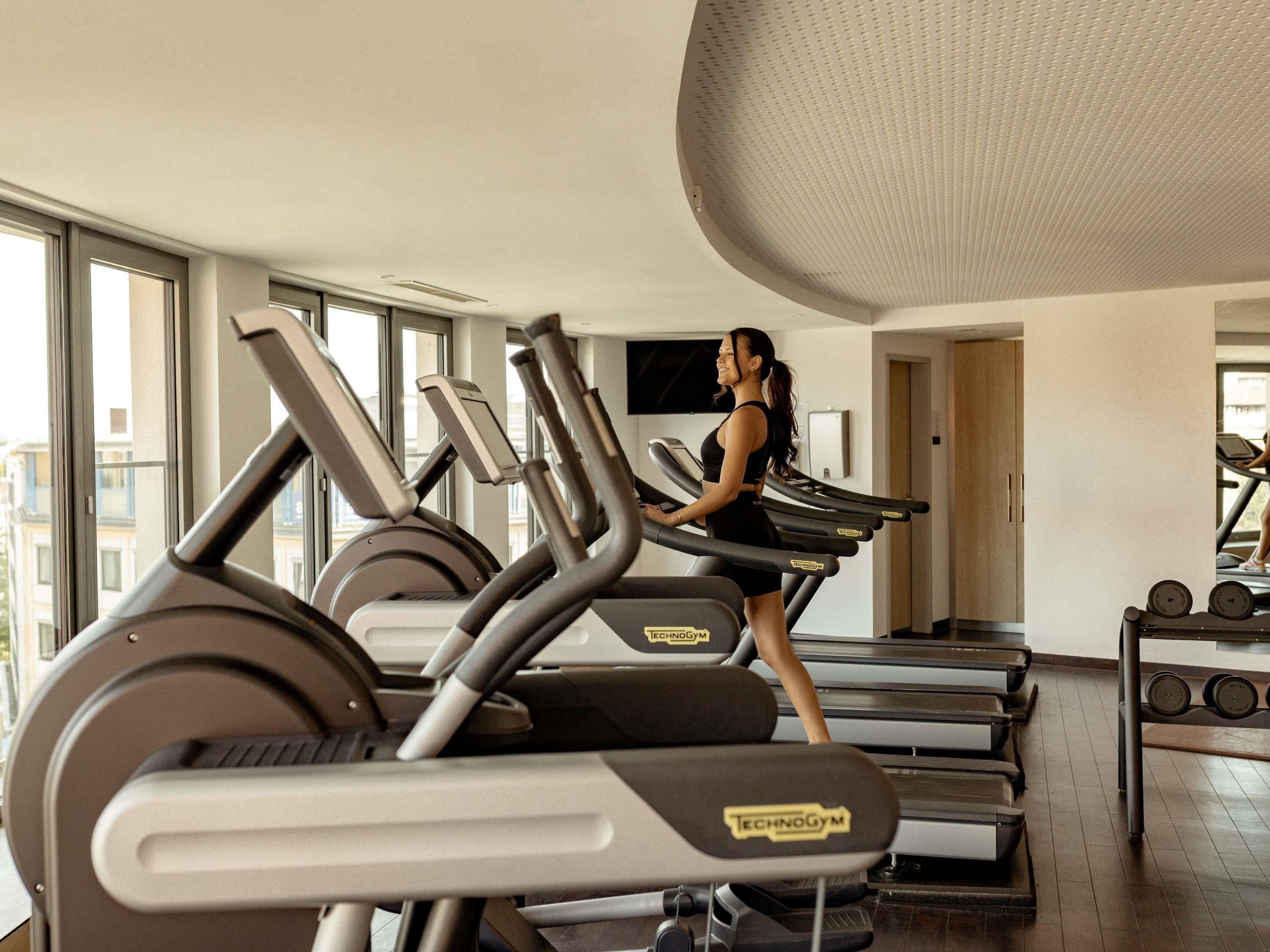 A gym with treadmills, weights, and a large window.