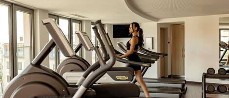 A gym with treadmills, weights, and a large window.