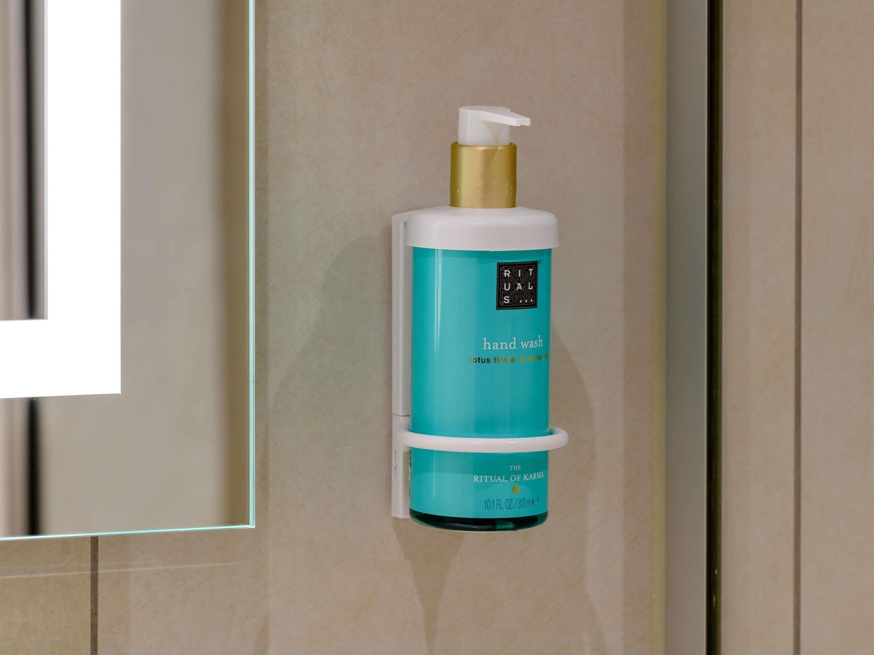 Un distributeur de savon liquide pour les mains, placé dans une salle de bain aux couleurs bleu sarcelle et blanc.