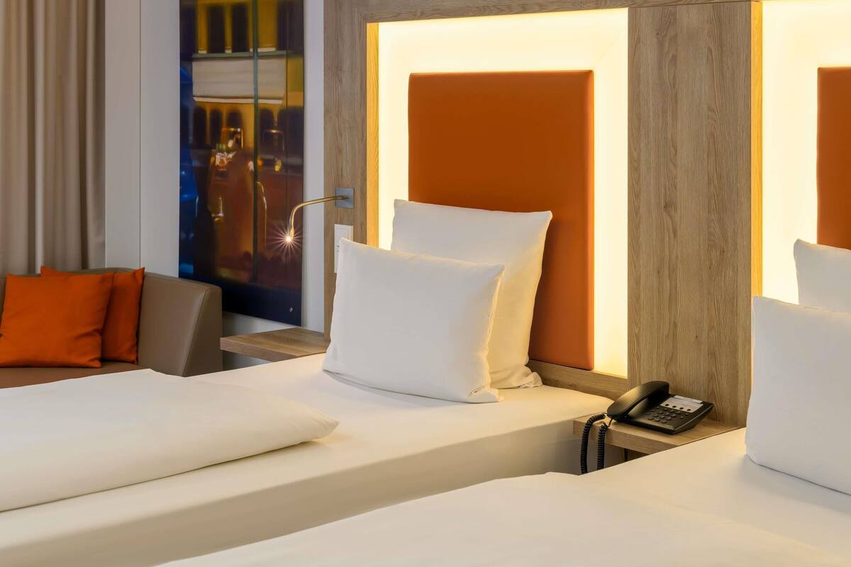 A hotel room with a bed, a bedside phone, and a nightstand.