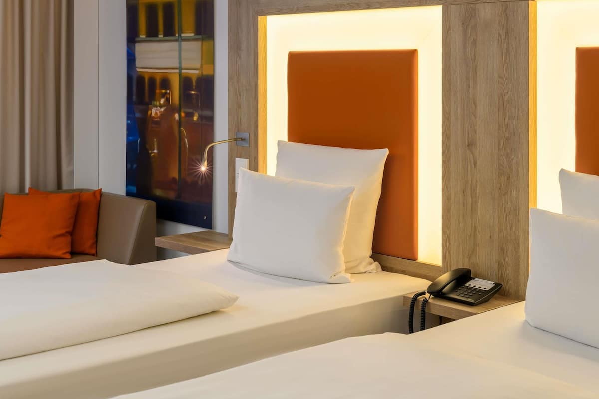 A hotel room with a bed, a bedside phone, and a nightstand.
