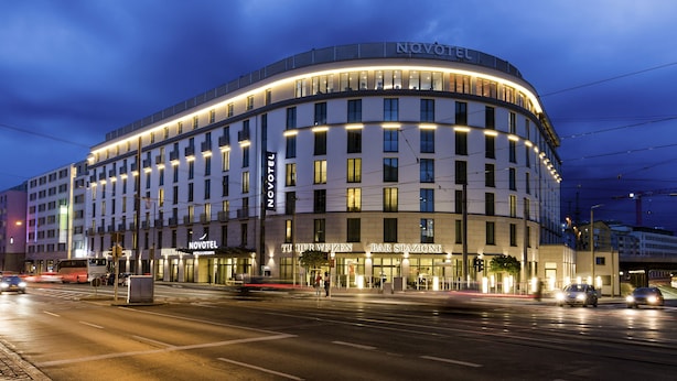 A modern hotel with a curved facade, multiple floors, and illuminated windows. - Novotel Nuernberg Centre Ville (Nuremberg)