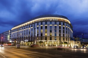 A modern hotel with a curved facade, multiple floors, and illuminated windows. - Novotel Nuernberg Centre Ville (Nuremberg)