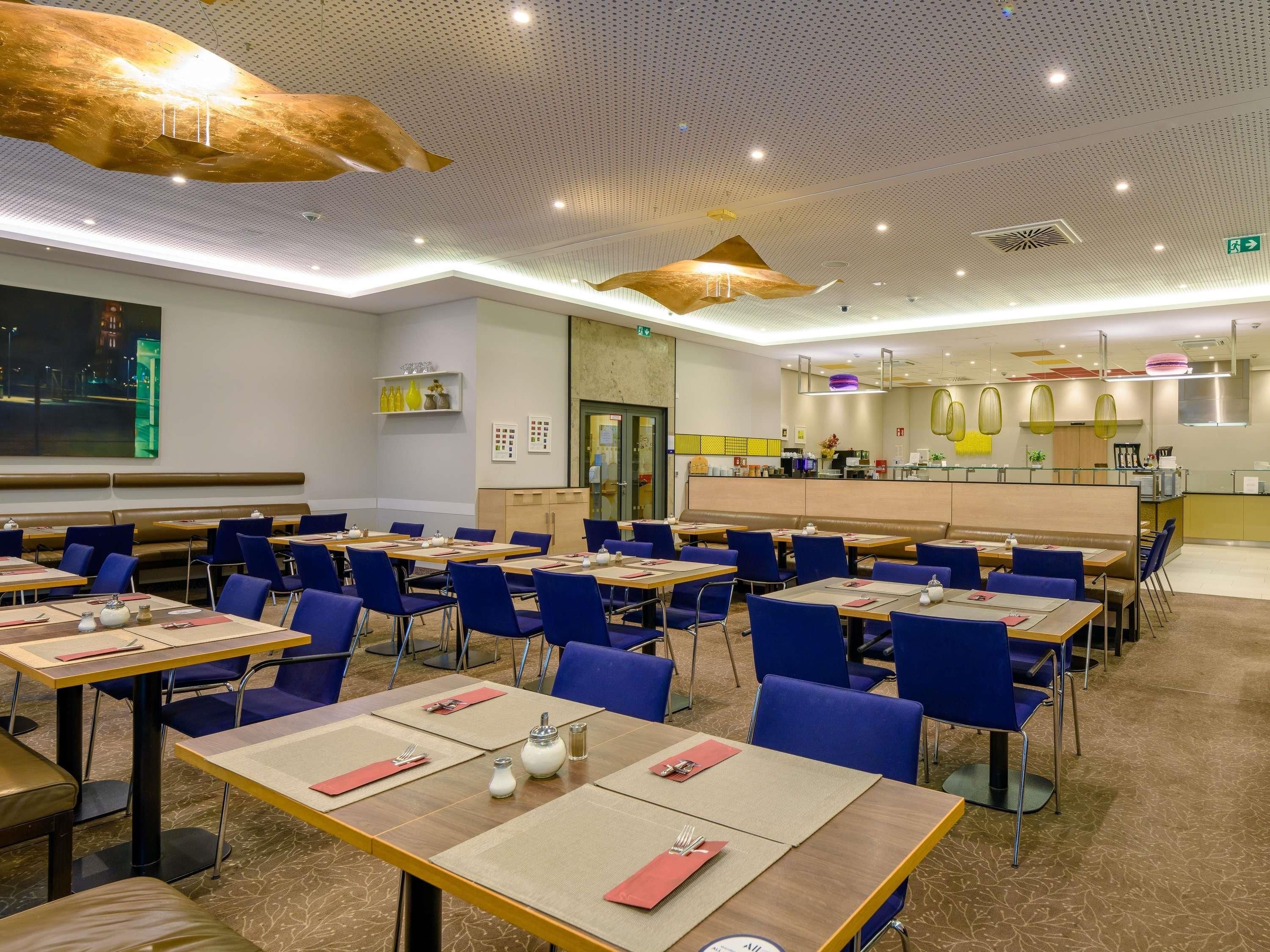 A restaurant with multiple tables and chairs, a counter area, and a kitchen in the background.