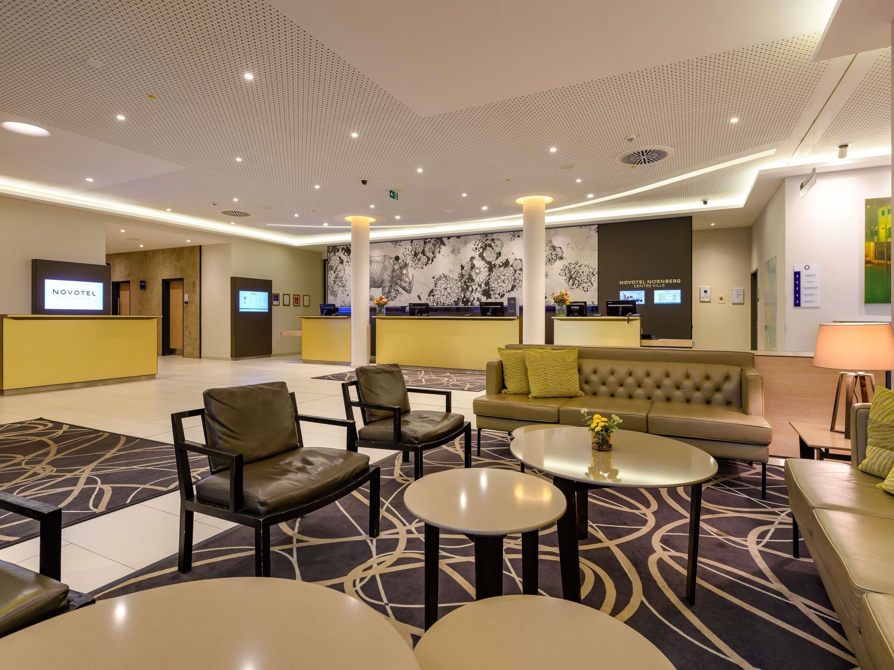 Een hotel lobby met een receptiebalie, een zithoek en een groot muurdecoratie.