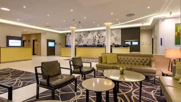 A hotel lobby with a reception desk, seating area, and a large wall mural.