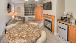 A modern kitchen with a dining area, a fireplace, and a flat-screen TV. - Accommodation By Willow Brook Lodge (Pigeon Forge)