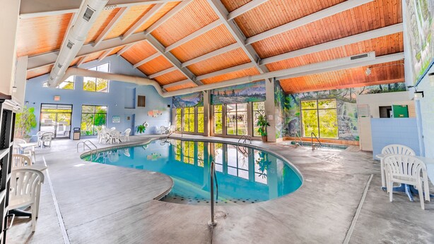 An indoor swimming pool with a wooden ceiling and large windows. - Accommodation By Willow Brook Lodge (Pigeon Forge)