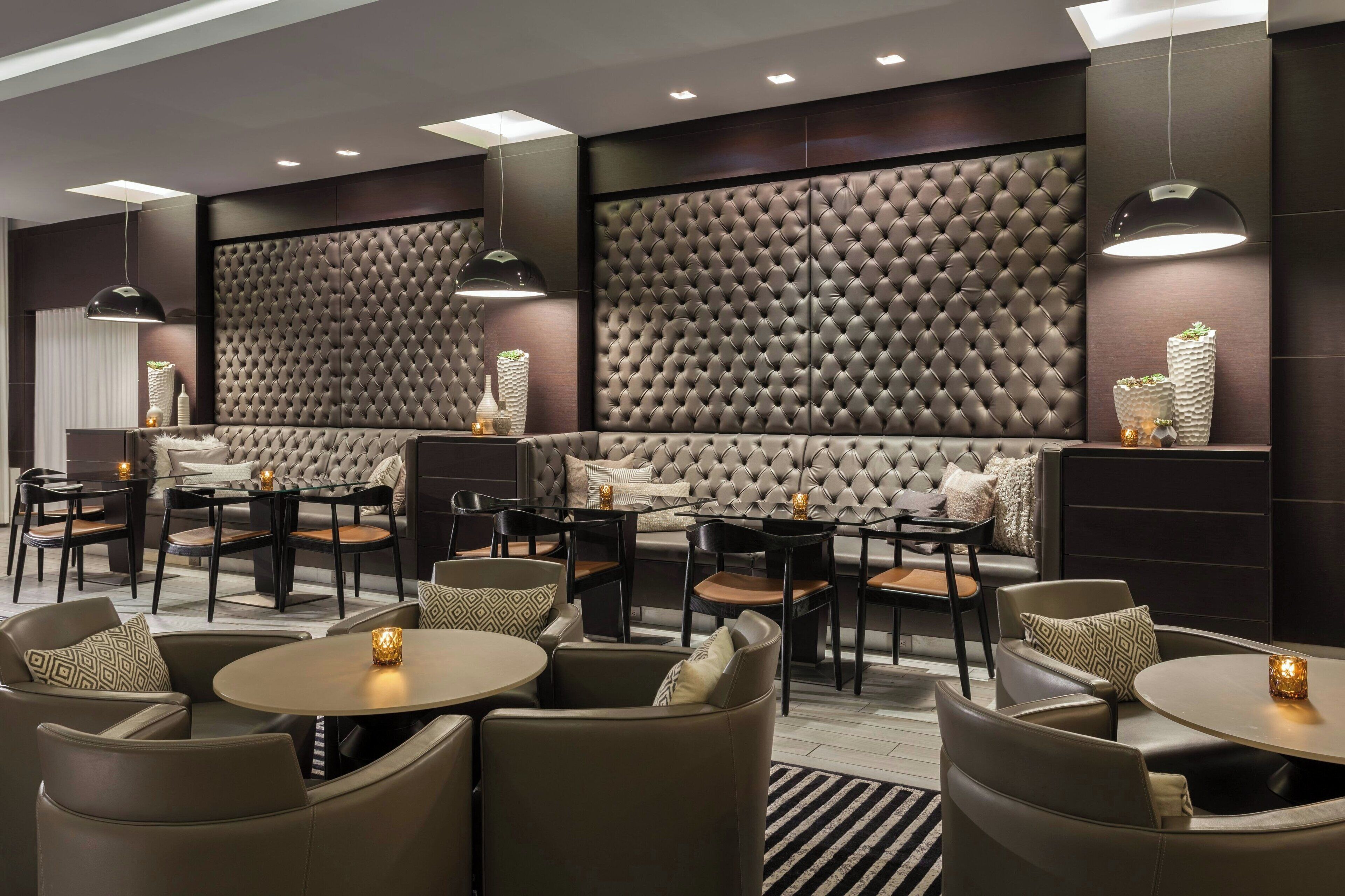 A modern lounge area with leather sofas and armchairs, a coffee table, and pendant lighting.