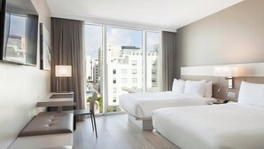 A modern hotel room with two beds, a seating area, and a large window offering a city view. - AC Hotel by Marriott Miami Beach (Miami Beach)