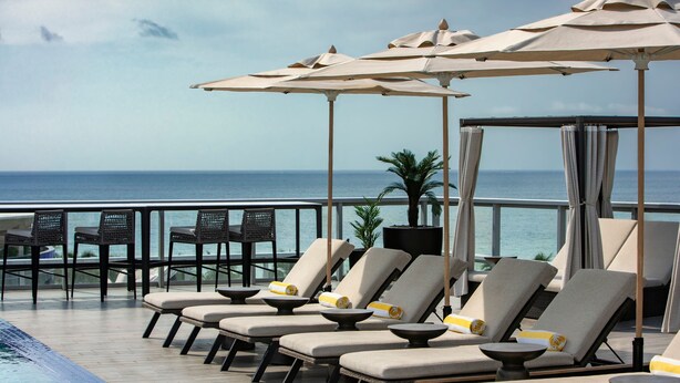 A poolside area with lounge chairs and umbrellas, overlooking the sea. - AC Hotel by Marriott Miami Beach (Miami Beach)
