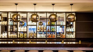 A bar area with multiple shelves of liquor bottles, a marble countertop, and bar stools. - AC Hotel by Marriott Miami Beach (Miami Beach)
