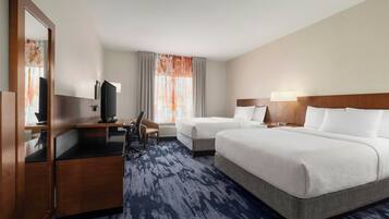 A hotel room with a bed, a desk, a chair, a television, and a large mirror.
