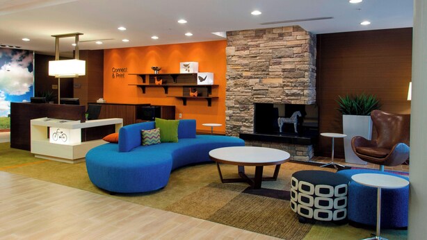 Un hall d’entrée moderne avec un canapé bleu, une cheminée, un comptoir de réception et un mur décoratif en pierre.
