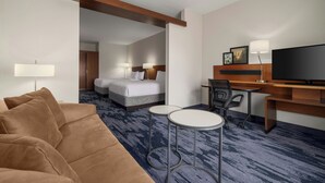 Une chambre d’hôtel comprenant un lit, un canapé, un bureau avec une chaise, une télévision et une lampe.