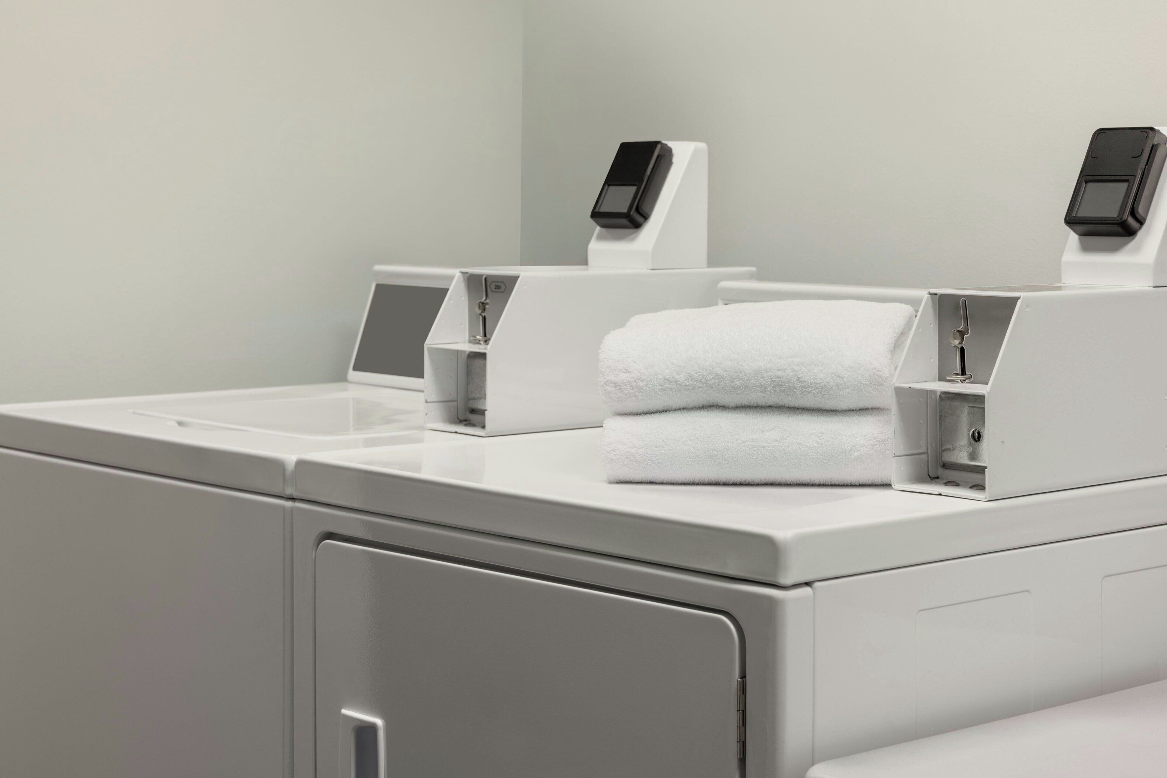 Een moderne badkamer met een wit wastafel, een zeepdispenser en een digitale weegschaal.
