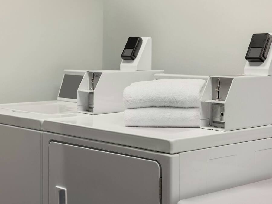 Een moderne badkamer met een wit wastafel, een zeepdispenser en een digitale weegschaal.